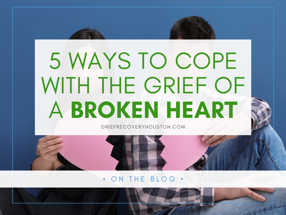 A graphic that reads "5 Ways to Cope with the Grief of a Broken Heart" over a stock photo of a couple sitting in front of a blue background, each holding one half of a paper broken heart. | Therapy for breakups in Houston