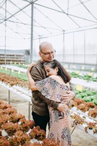 A stock photo of two adult white people embracing in a plant nursery.