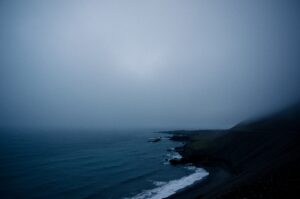 A dark and kind of gloomy photo of a cloudy rocky shoreline. 
