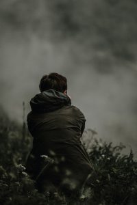 A stock photo of a person sitting in a foggy landscape.