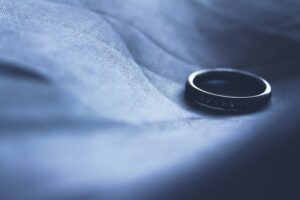 single wedding band symbolizing divorce on a soft blue sheet